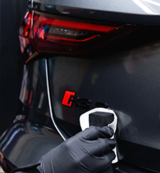 Detailer werkt met handschoen aan de lak van een zwarte auto